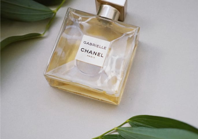 Gabrielle's perfume on a table with two branches around it.